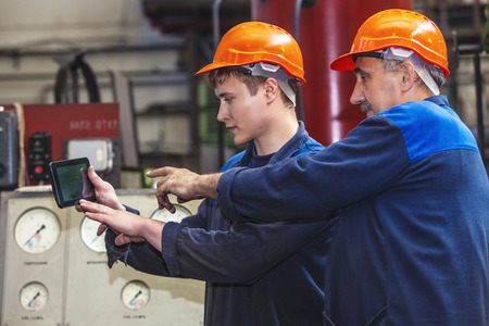 Men work on the old factory for the installation of equipment in protective helmets