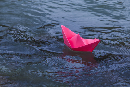 Pink boat floating in the blue water with the flowの写真素材