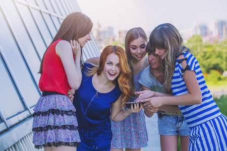 Female friends looking at smartphone on the modern building backgroundの写真素材