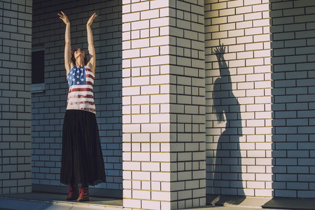 Female model on the background of a city building in a t-shirt with an American flagの写真素材
