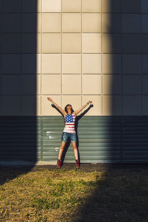 Female model on the background of a city building in a t-shirt with an American flagの写真素材