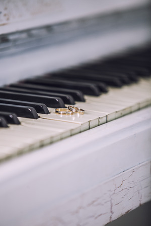 Wedding gold rings on the white keys of the piano. Ceremony, religion, music, vintage, custom, decoration.の写真素材