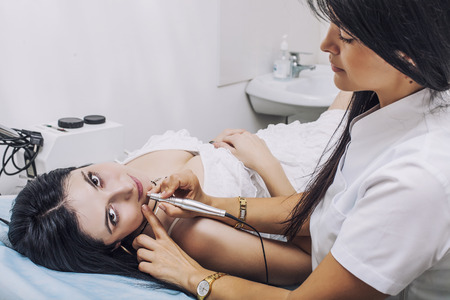 Salon where the woman makes tattooing a client on the couch. Beauty, fashion, cosmetic, employee, customer, communication.の写真素材