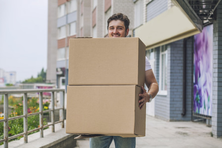 Porter, the man with cardboard boxes in the hands of a strong, delivery to the door. Fast delivery, reliability, deliveryman.の写真素材