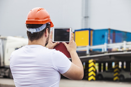 Builder man working with a tablet in a protective helmet. Construction, safety, performance.の写真素材