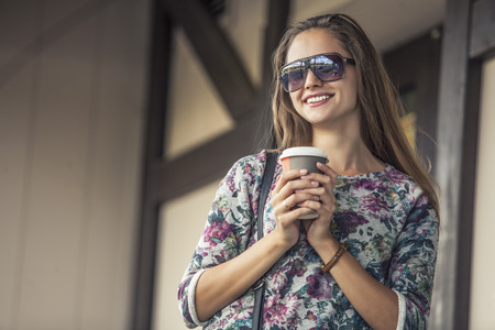 Beautiful woman model with take-away coffee on the street. Style, casual, restaurant, drinks, pastriesの写真素材