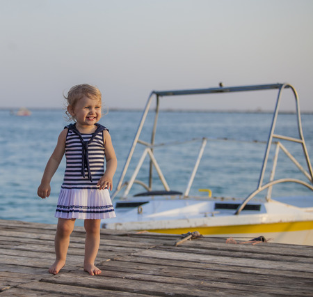Portrait of a child with golubymi eyes on the pier at the boat. Summer, happiness, sea, oceanの写真素材