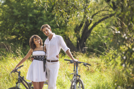 Couple man and woman in wedding style with bikes in nature happyの写真素材