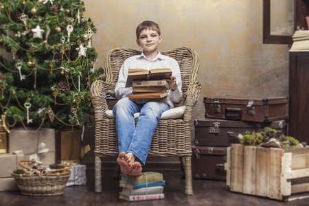 Cute baby in a chair reading a book in a Christmas retro interior