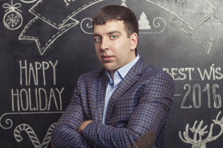 Portrait of a man in a jacket against the wall inscribed with Christmas wordsの写真素材