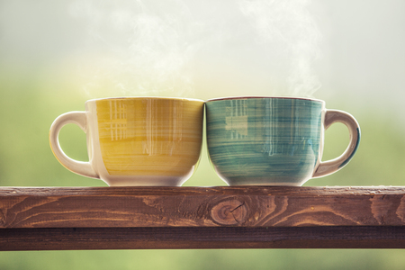 Mugs with a hot drink with tea on a wooden stand outdoors in the countrysideの写真素材