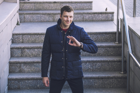 Male model in trendy modern youth warm jacket in the urban landscape on the background of stairsの写真素材