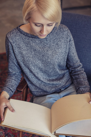 Woman young beautiful student with the album thinking about new ideas sitting at the tableの写真素材