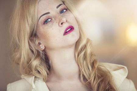 Female model with freckles on her face with bright pink lips closeup portraitの写真素材