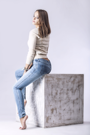 Model, woman in fashionable jeans and a jacket in full length in Studio on interior cube on a light backgroundの写真素材