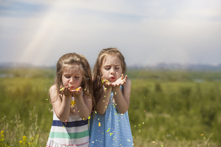 Two little girls are pretty children in nature happy smiling colorful balloons and confetti in the sunlightの写真素材