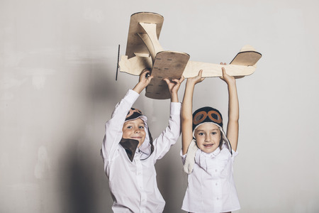 Boy and girl with wooden model airplane and a cap with cap designs in the Studioの写真素材