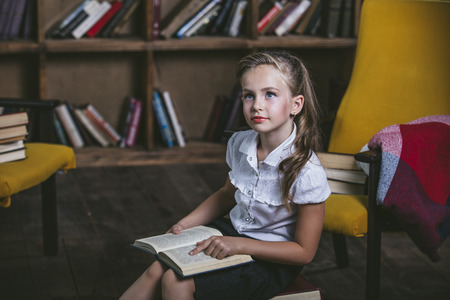 Girl child in the library with books in a strict fashion is engaged in education and trainingの写真素材