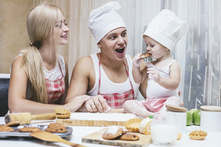 Family, happy daughter with dad and mom in home kitchen laughing and preparing food together, with loveの写真素材