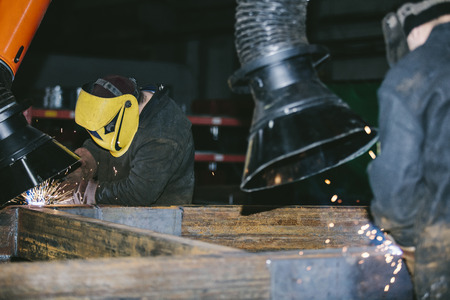 Worker at the factory in the helmet is of iron in the welding process bright sparks