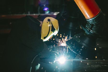 Worker at the factory in the helmet is of iron in the welding process bright sparks