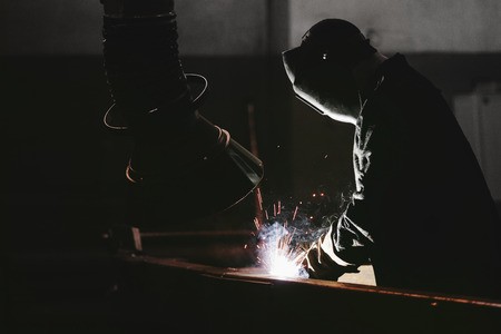 Worker at the factory in the helmet is of iron in the welding process bright sparksの写真素材