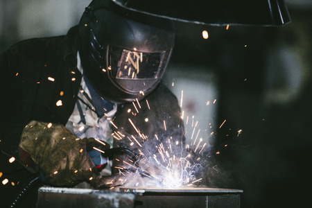 Worker at the factory in the helmet is of iron in the welding process bright sparksの写真素材