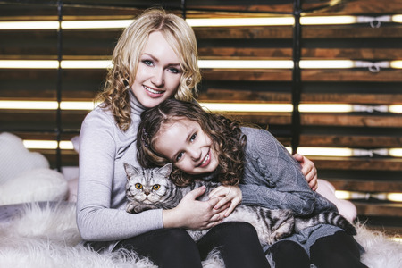 Fashion cute little girl and beautiful woman with a British kitten in the arms of very happy togetherの写真素材