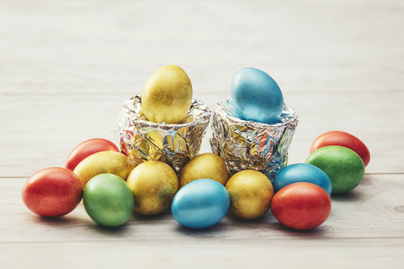 Colorful Easter eggs with stands of silver foil on a wooden table