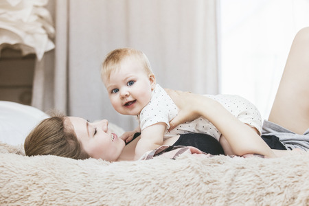 Mother and little baby in bed and woke up in the morning and smiling at home
