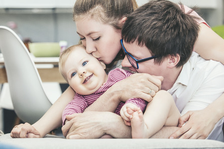 Family mother father and baby are happy together at home smiling portrait