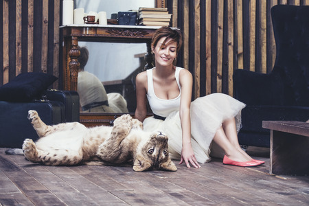 Beautiful fashionable young woman with a cute little alive lion cubの写真素材