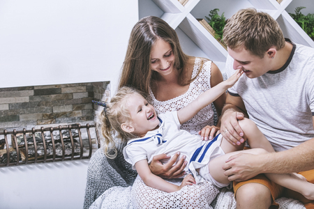 Happy beautiful young family father, mother and daughter fashion smiling together at homeの写真素材