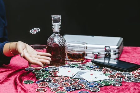 Beautiful young woman with a successful gambling tablet, online casino at a table with cards, chips...