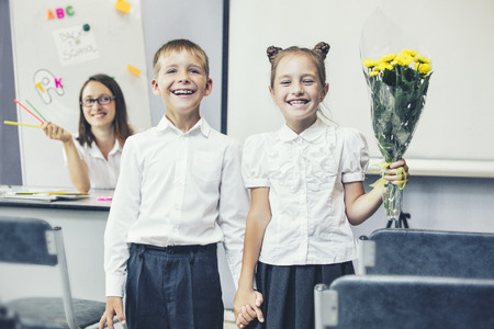 Beautiful children school children with flowers for the teachers at school on a holidayの写真素材