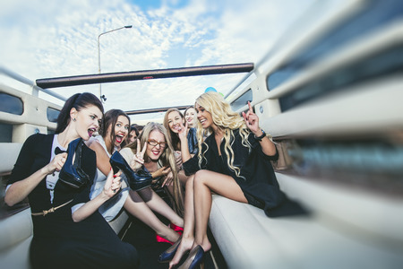 Young beautiful happy women celebrate bachelorette party in a convertible limousineの写真素材