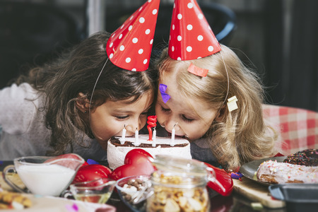 Two happy little girls child celebrating a birthday with cake at the table is lovely and beautifulの写真素材