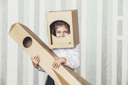 Child little girls playing spaceman with a cardboard rocket and a cardboard helmetの写真素材