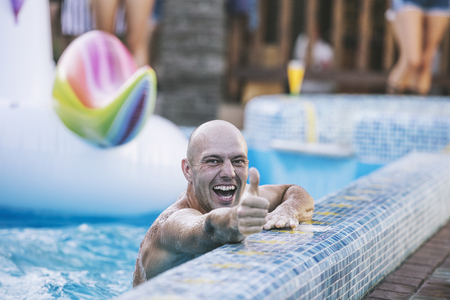 Young adult man smiling happy swimming in the pool at the partyの写真素材