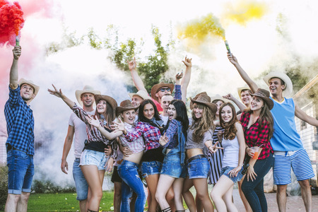 Friends happy at the party funny young together with smiles and crackers with colored smoke