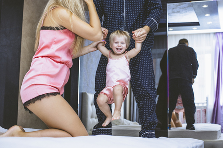 Family at home in the bedroom mom, dad and baby are happy together in the morningの写真素材