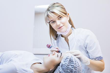 Beautician female applies permanent makeup on eyebrows, tattoo eyebrows on beautiful models in a beauty parlorの写真素材