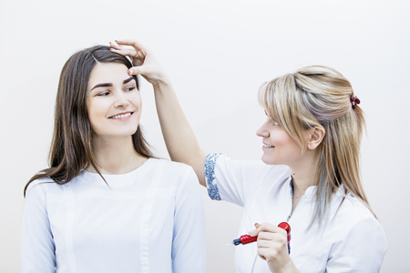 Beautician woman and her lucky client model in permanent eyebrow makeup and face care officeの写真素材