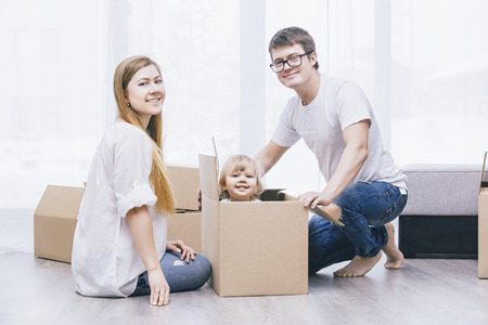Family together happy young beautiful with a little baby moves with boxes to a new home