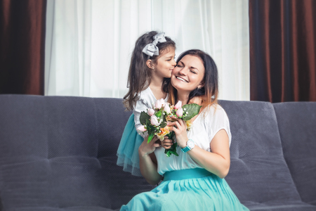 Little cute daughter gives flowers to mom on mother's day at homeの写真素材