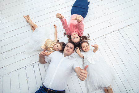 Family happy mom, dad and two girls twin sisters at home on a white wooden floor.の写真素材