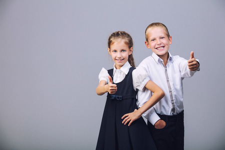 Kids boy and girl in school uniform fashionable beautiful and confident in Studio on grey backgroundの写真素材