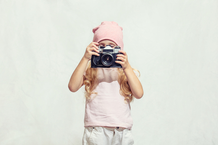 Little child girl is beautiful fashionable and happy with camera in hand on isolated backgroundの写真素材