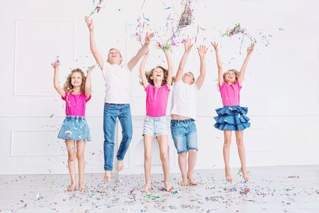 Happy beautiful cute kids smile at the holiday party with confetti together in the white roomの写真素材