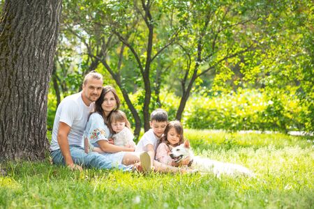 Happy beautiful big family together mother, father, children and dog walking on a Sunny summer dayの写真素材